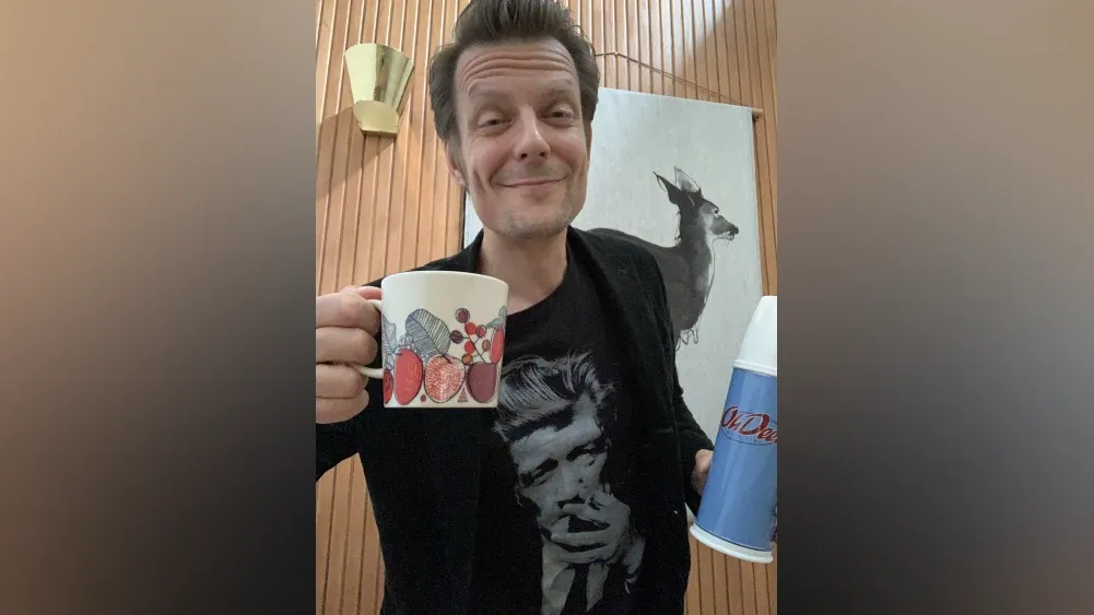 Sam Lake from Remedy Entertainment holding a cup of coffee and smiling.