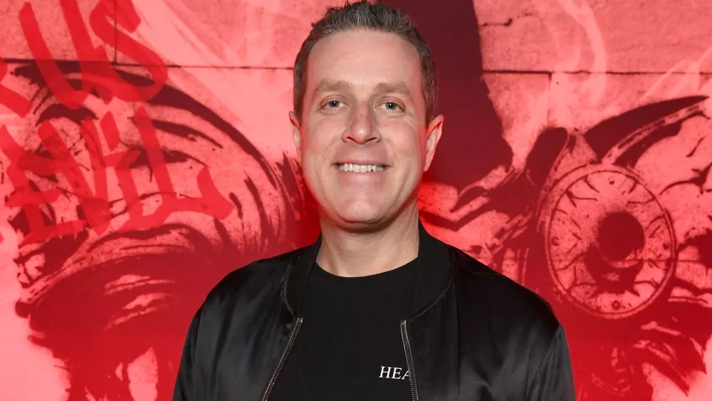 Geoff Keighley standing in front of a red background.