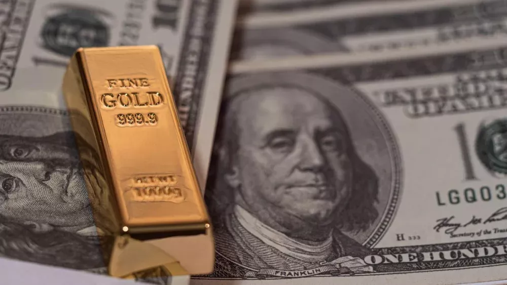 A gold bar on top of several $100 bills.
