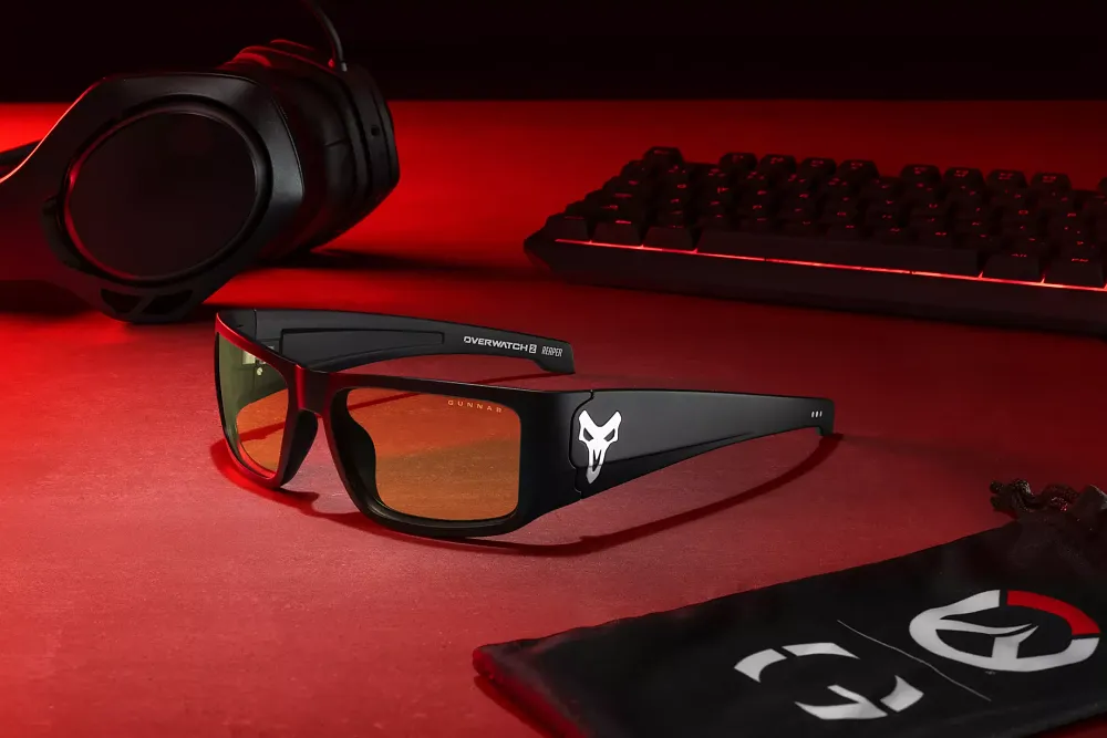 A pair of Gunnar gaming glasses that are black with the Overwatch Reaper icon on the side. The lenses are slightly tinted yellow-orange.