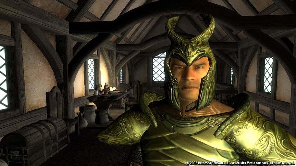 A man in golden armor staring at the viewer. He is inside of some sort of a fantasy-medieval style room with wooden arches, a wooden chest on the left, a wooden table and chairs, and several windows.