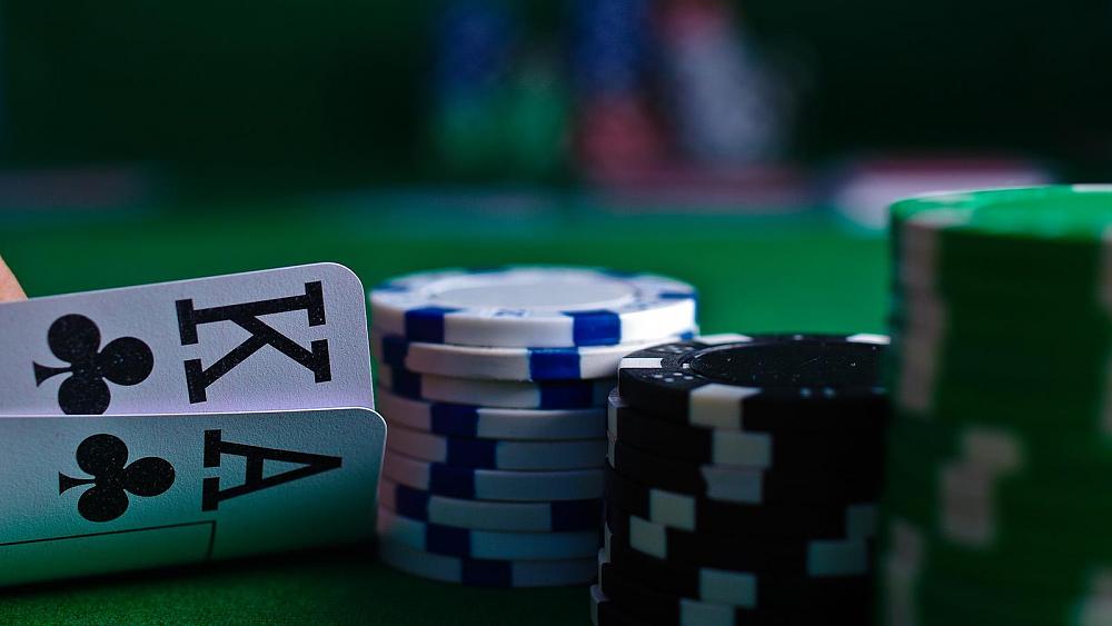 A king and an Ace playing cards next to three stacks of poker chips.