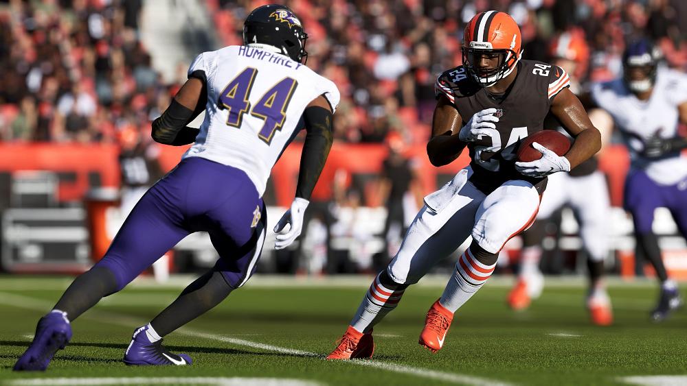 An American pro football player holding a football is trying to evade a tackle from an opposing player.
