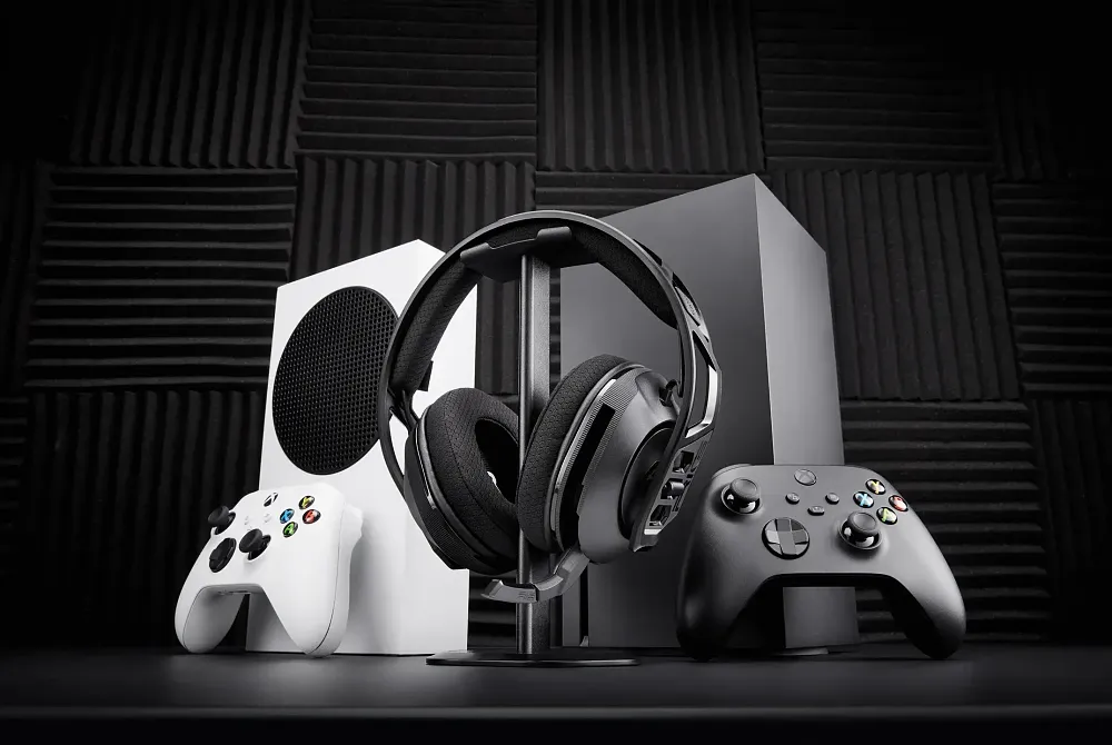 Wireless headphones in front of an Xbox Series S and Xbox Series X.