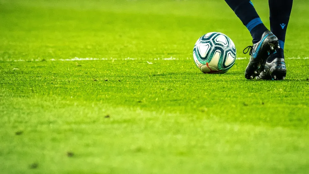 Photo of a soccer player's feet about to kick a soccer ball.