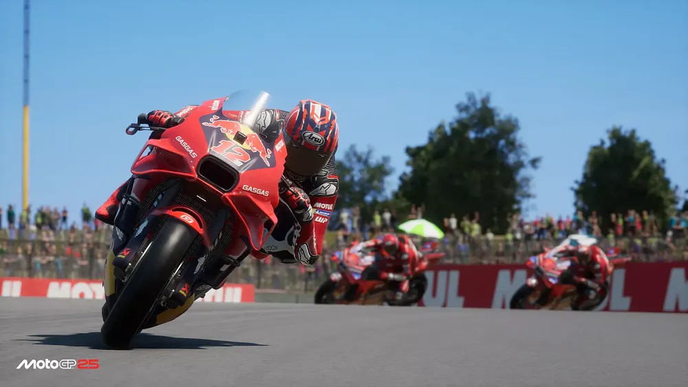 A MotoGP rider on his bike riding in a race. They are speeding towards the camera view and leaning into a turn.