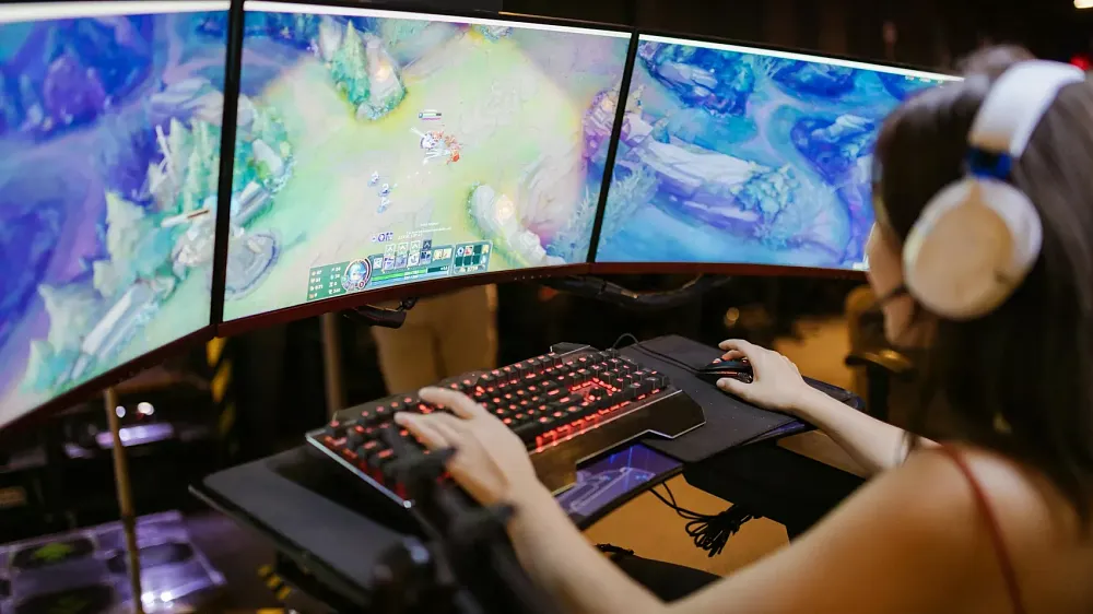 A person playing a game on a computer with three monitors.