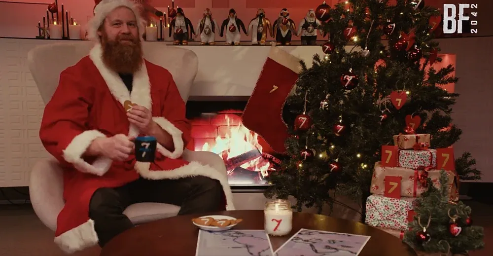 A man dressed as Santa surrounded by ornaments and cookies all with the number 7 on them.