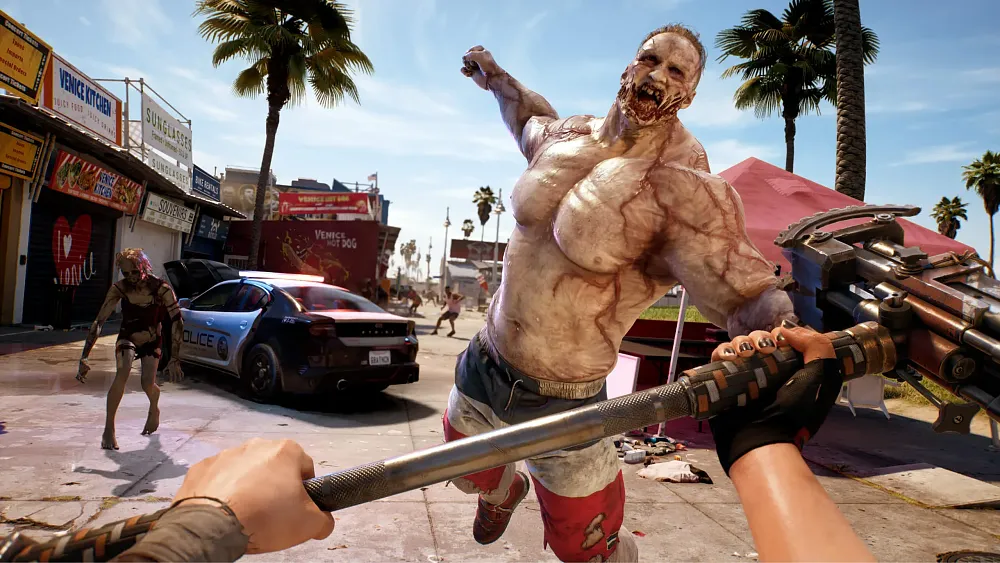 A large, muscular zombie is jumping towards the camera ready to strike with his fist. Other zombies shamble around on what appears to be a boardwalk with shops and storefronts.