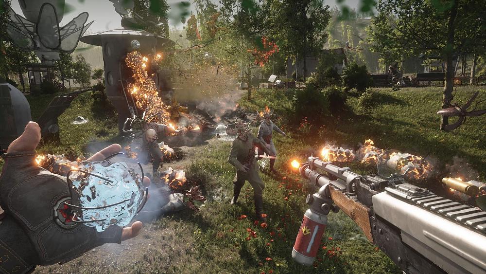 The view looking out from a person holding a flamethrower in their right hand and a liquid orb in their left. They are in a park and seem to be fighting mutated creatures.