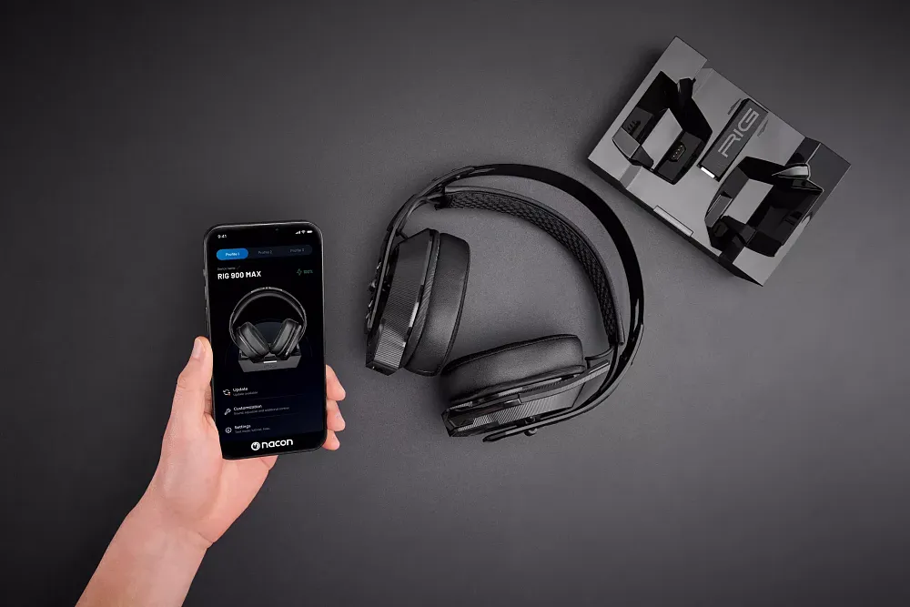 A photo of a new wireless headset, a charging base station, and someone's hand holding a mobile phone showing an app for customizing the headset audio.