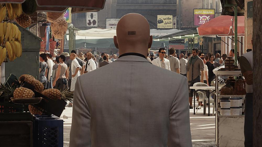 A bald man with a barcode on the back of his head walking through a crowded street market.