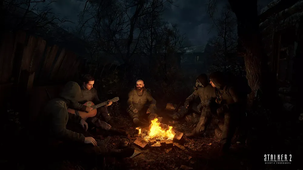 A small group of men sitting around a campfire at night, one is playing a guitar.