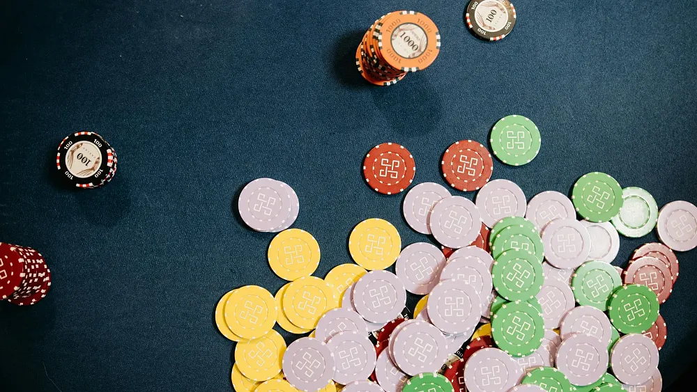 Photo of gambling chips, of various colors, on a table. Source is pexels.com.