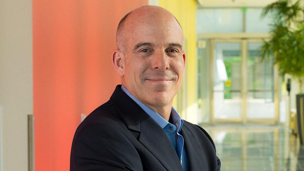 A middle-aged, bald man smiling.
