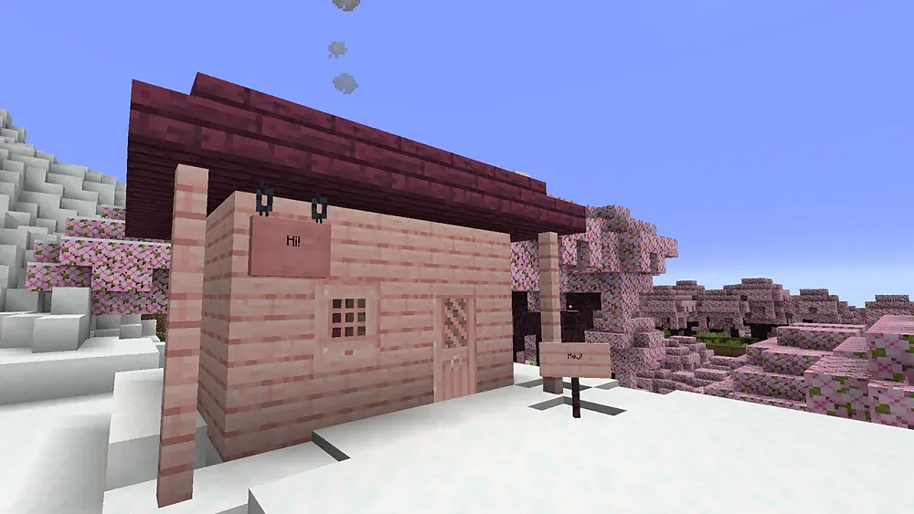 A small pink house made of pink wood, with a pink door, and pink window frame sitting in a snowy biome. A pink sign on the house reads hi. Behind the house is a biome full of pink cherry blossom trees.