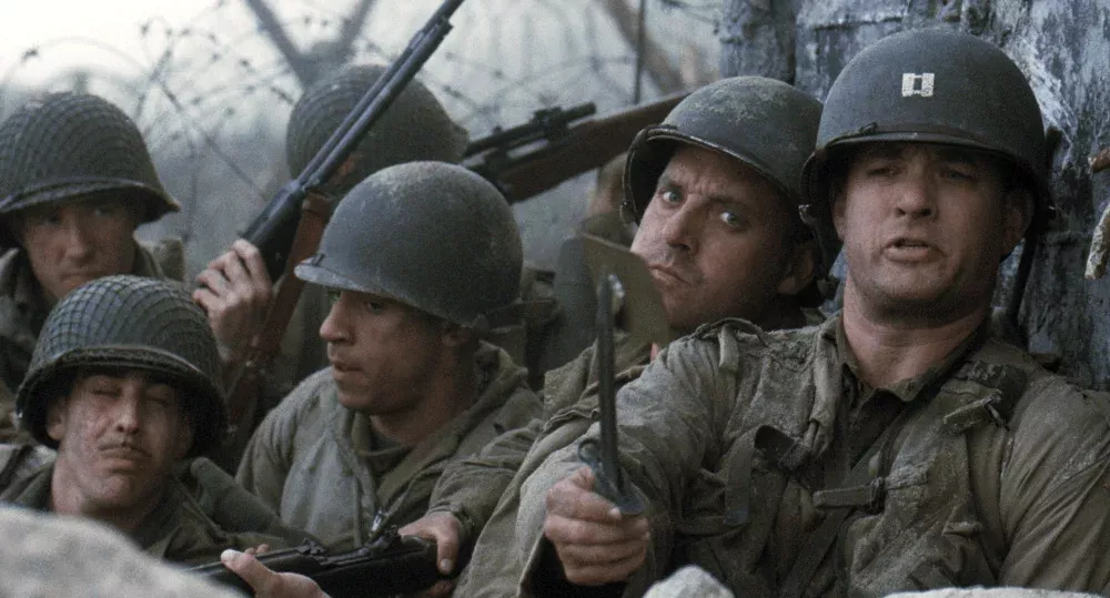 A still from Saving Private Ryan showing several soldiers huddled together trying to stay safe from enemy gunfire.