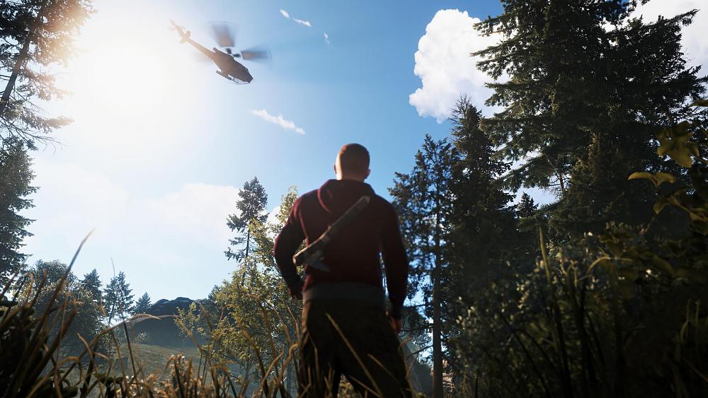 A person standing in a forest looking up at a helicopter flying overhead.