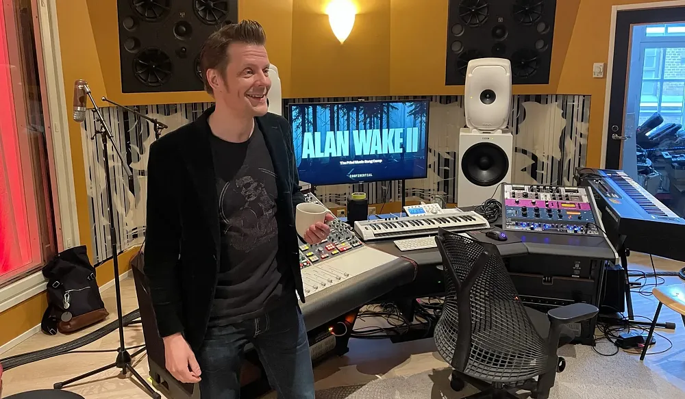 Sam Lake from Remedy holding a coffee cup in a music recoding booth.