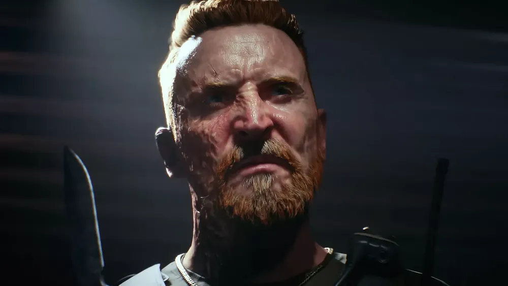 A possibly evil man with a scarred right side of his face is holding up a knife and looking somewhat angrily off camera.