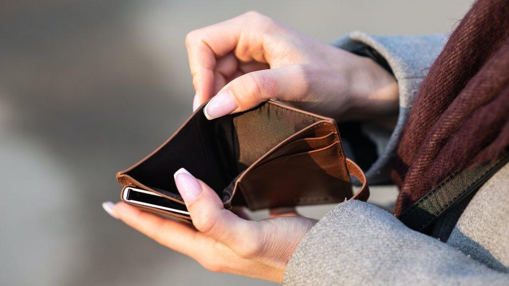 A person holding open an empty wallet.