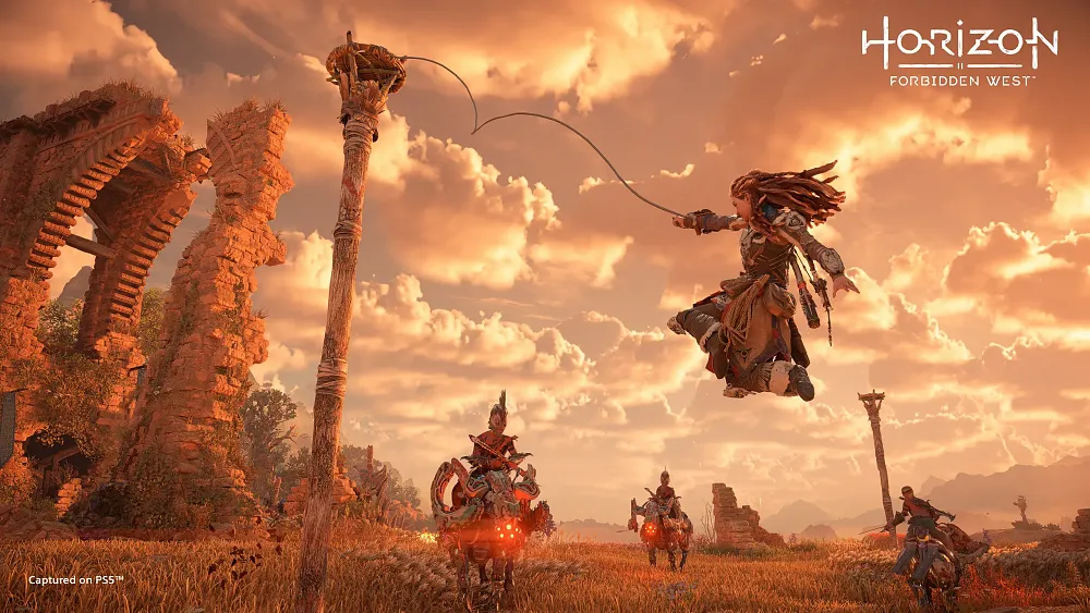 Screenshot from a game showing a red-haired woman warrior tossing a grappling hook at a tall poll to escape enemy warriors who are riding robotic dinosaurs