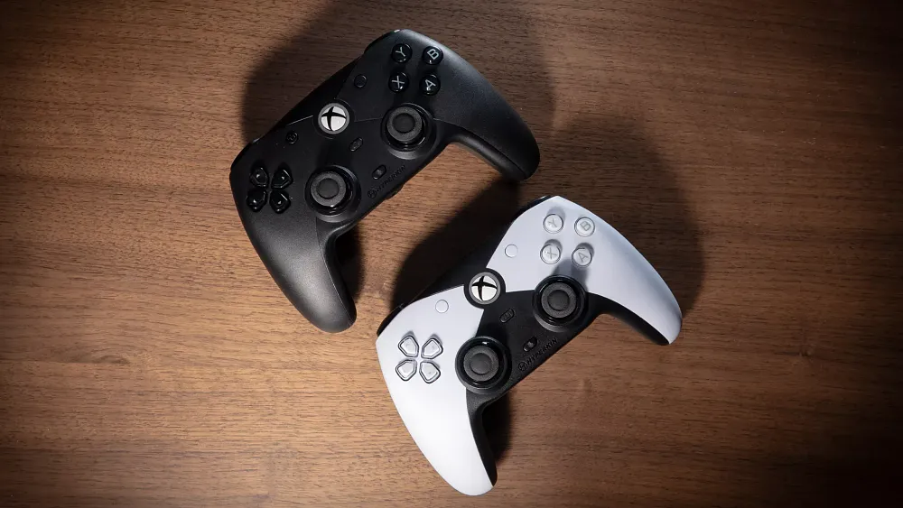 Top-down photograph of two game controllers, one white and one black. They are both The Contender from Hyperkin.