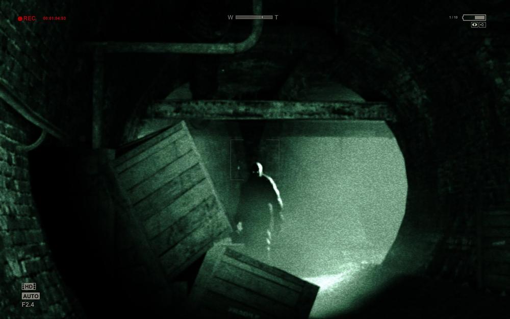 A night vision style image showing a large person standing at the end of a dimly lit sewer.