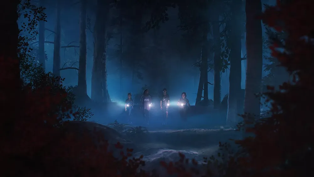 Four young women, teens, walking through a very dark forest. Each is shining a flashlight in front of them, towards the camera view.