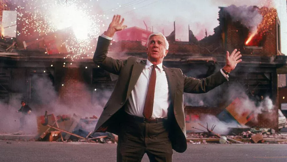 Scene from The Naked Gun with Frank telling people to move along  in front of exploding fireworks.