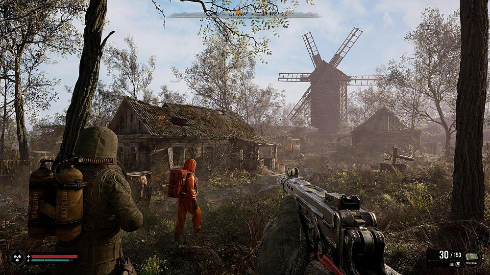 First-person view of a person holding an automatic weapon, following two companions that are dressed in hazmat style gear walking through a desolate, small village.