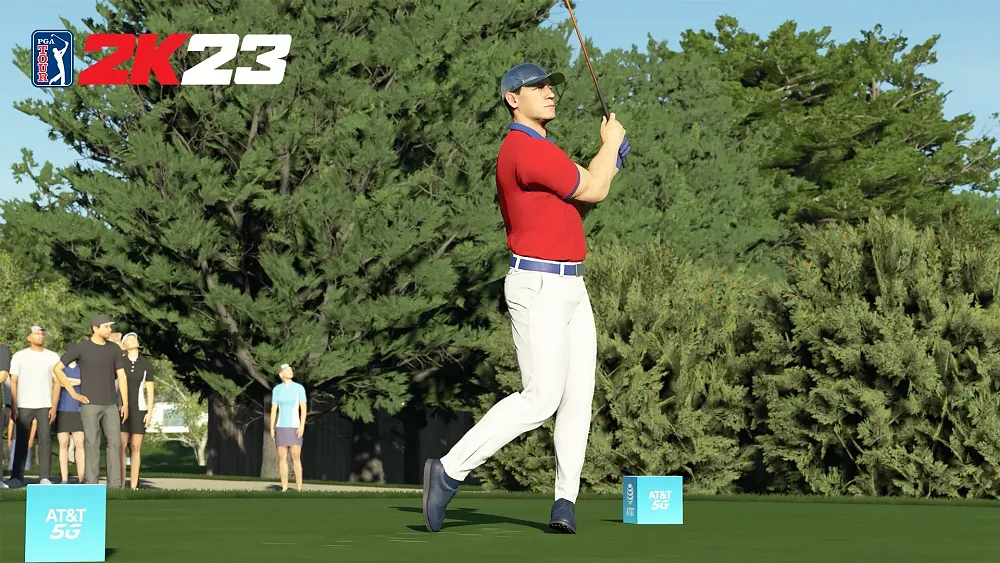 A golfer after finishing his swing standing at the tee. He is dressed in red, white, and blue and is very muscular.