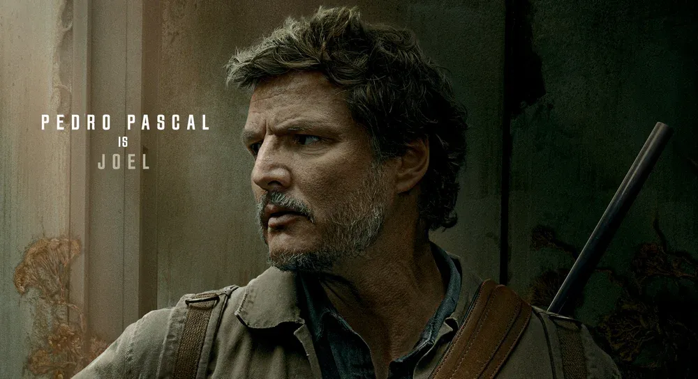 Closeup of a man with greying hair, scruffy beard, and a gun on his back looking off to the left out of frame