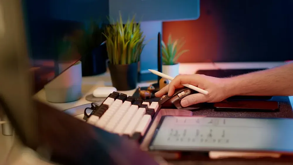 Closeup of a computer desk showing keyboard and someone using a mouse.