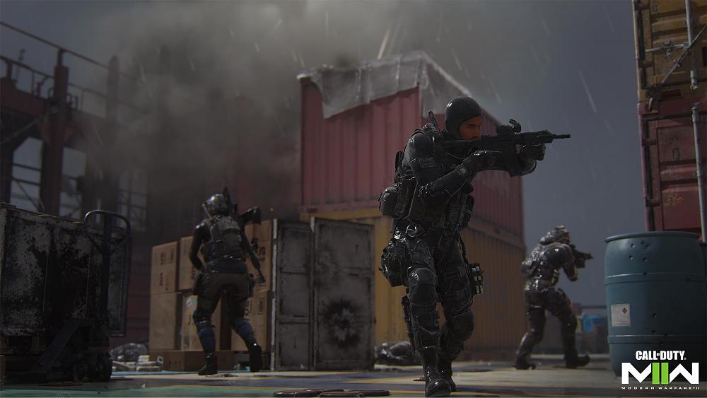 Screenshot from a video game showing various soldiers in different military style gear. Each are holding weapons as they walk around an environment filled with large shipping containers.