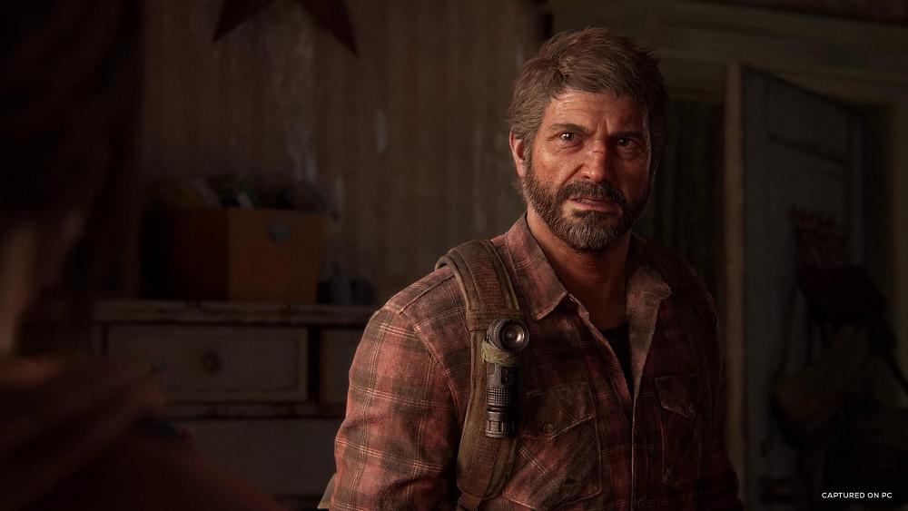 Bearded man in a faded red plaid shirt looking somewhat angry at a person slightly off screen in the foreground.