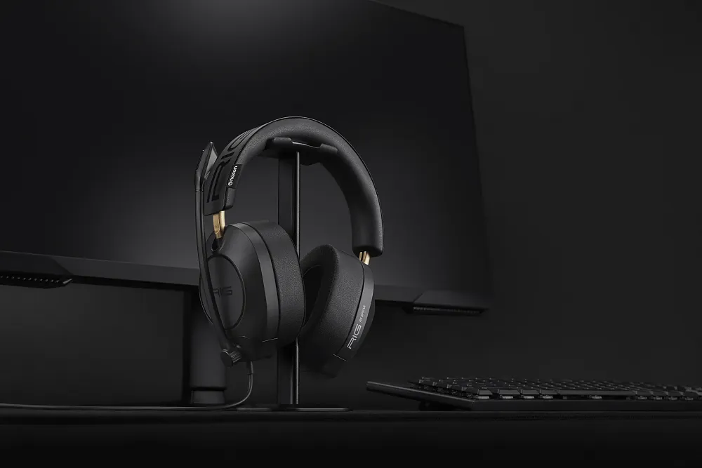 A photo of the new gaming headset from NACON, the RIG R5 Spear Pro Max HD, next to a computer. The headset is almost all black with thick ear cushions and a metal headband with cushioning.