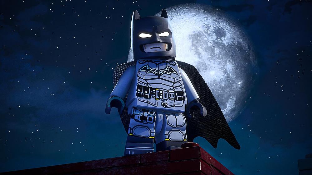 LEGO Batman standing on the edge of a building with the moon behind him.