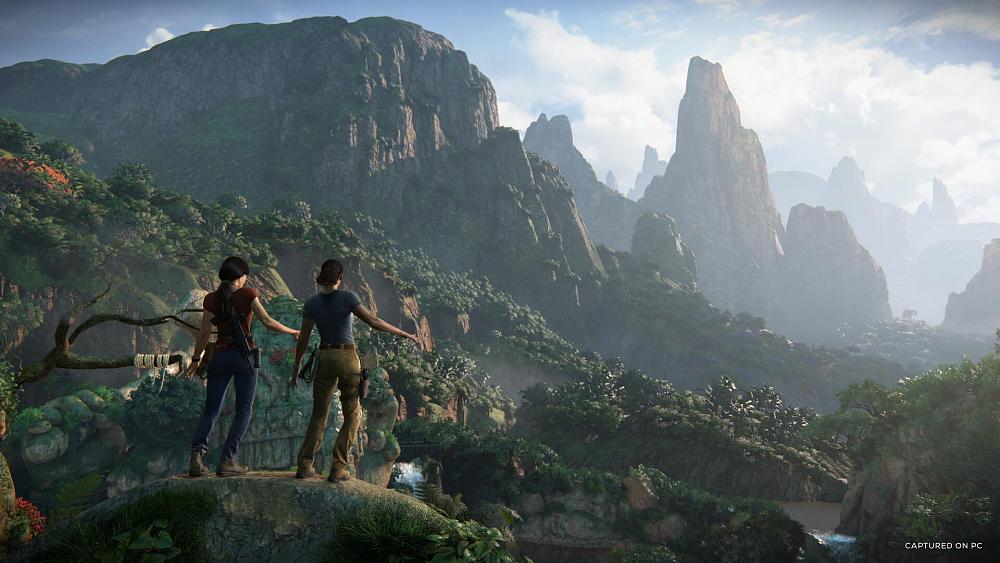 Two adventurers standing atop a statue looking out over a lush jungle and mountains.