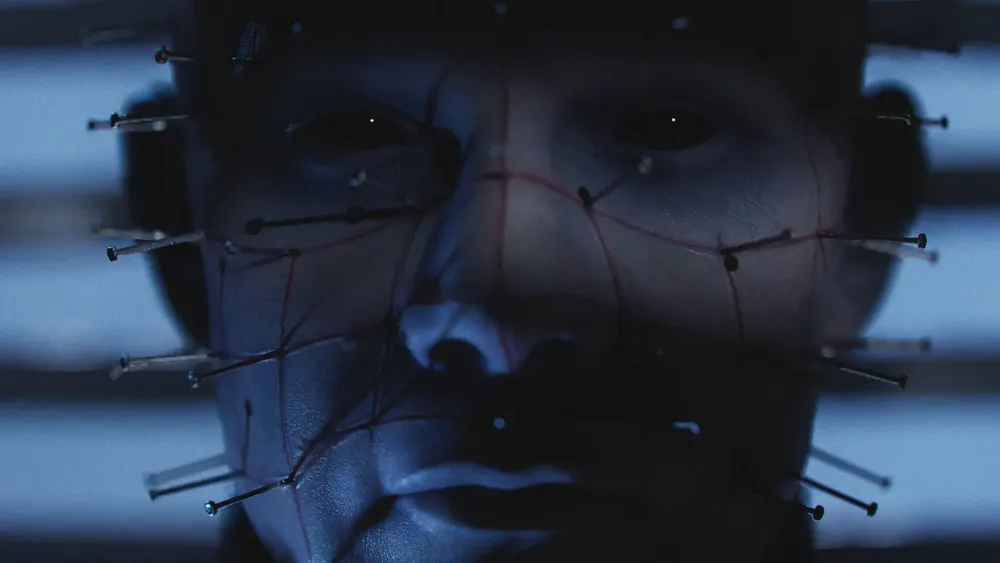 A closeup of Pinhead's face, a demon with screws arranged in a grid on his face, from Hellraiser.