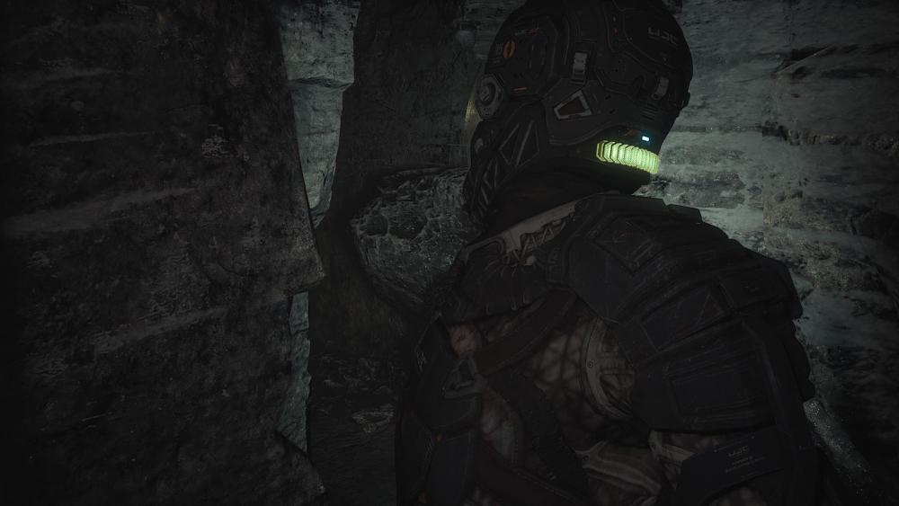 A man in a futuristic space suit shimmying through a narrow, rocky passage.