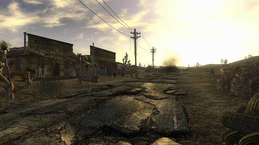 Looking down the street of a very small town of dilapidated buildings on one side of the street in Fallout: New Vegas.