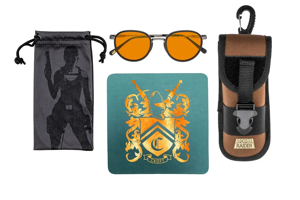 A pair of Amber Max tinted lenses on the Tomb Raider Croft Glasses from Gunnar along with several accessories such as a carrying case, soft cloth, and mini dagger.
