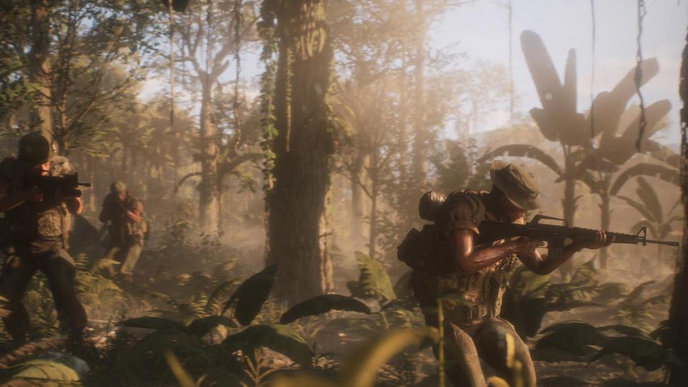 Soldiers in the Vietnam War walking with guns at the ready through a jungle.