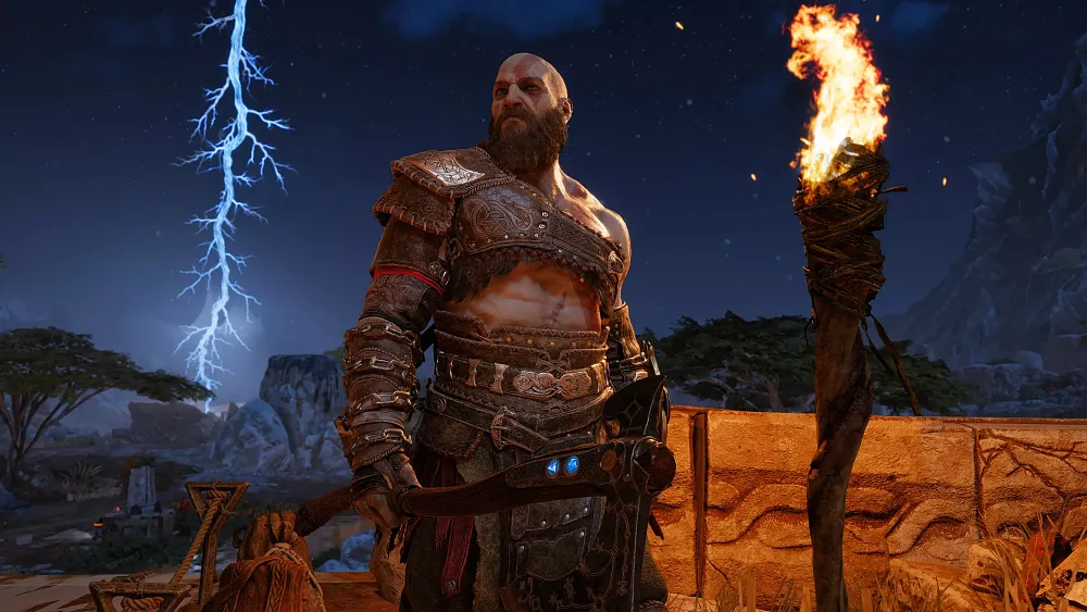 A very muscular bald but bearded man, Kratos, holding an axe standing near a lit torch while a frozen lightning bolt can be seen in the background.