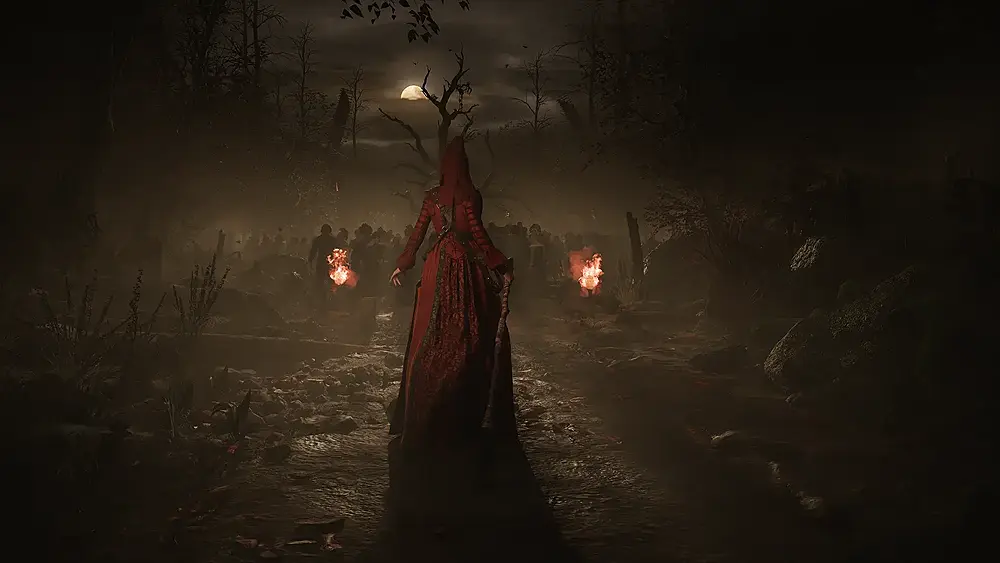 A witch in red standing in front of and facing a barren tree and a mob of people.