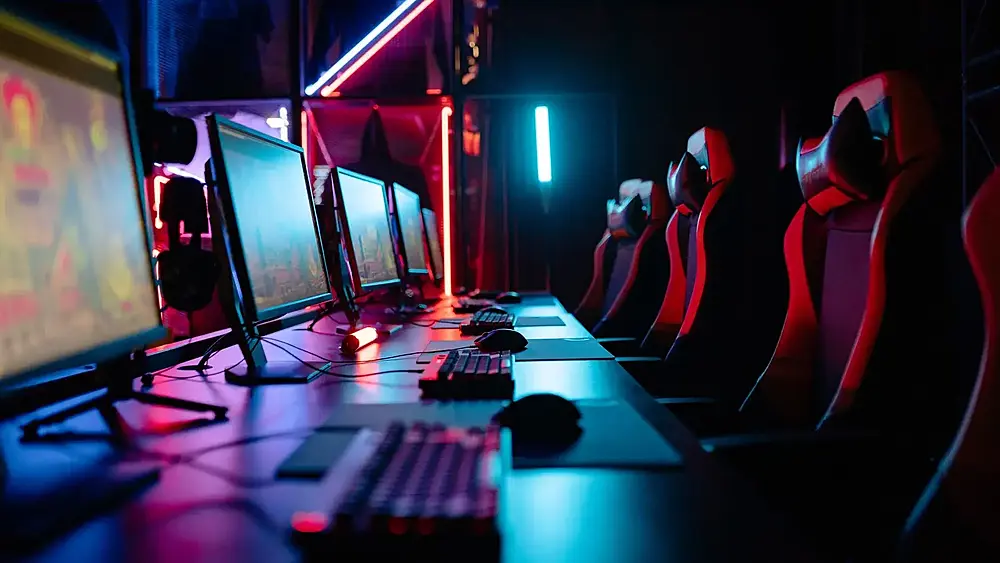 A gaming LAN center after hours with multiple computers setup and multiple gaming chairs in a row. Source: images.pexels.com