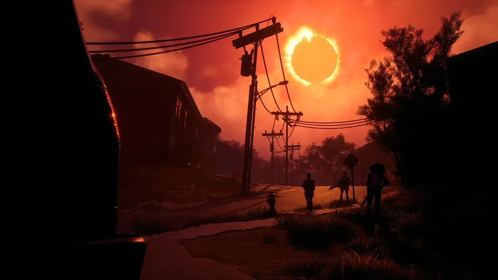 Screenshot from the game Redfall. The sky is red and there appears to be a solar eclipse happening. The silhouettes of three people, each holding weapons, can be seen as they walk up the road of a small town.