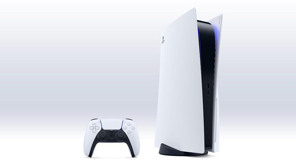 A PlayStation 5 console standing vertical on the right. On the left is a PlayStation 5 DualSense game controller.