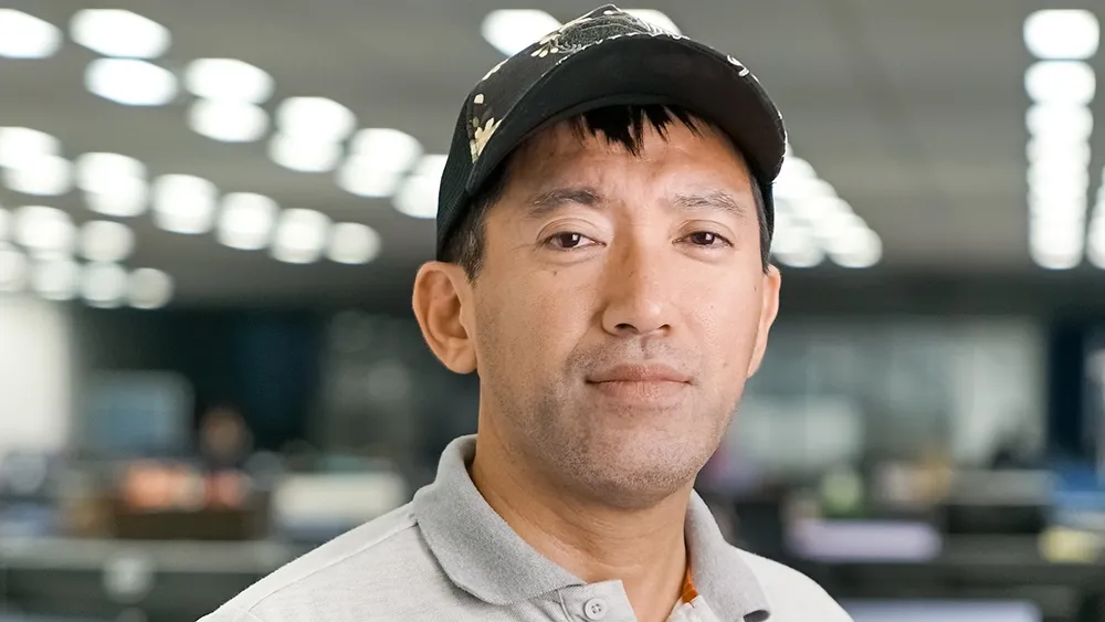 A photo of an Asian man wearing a black and white baseball cap.